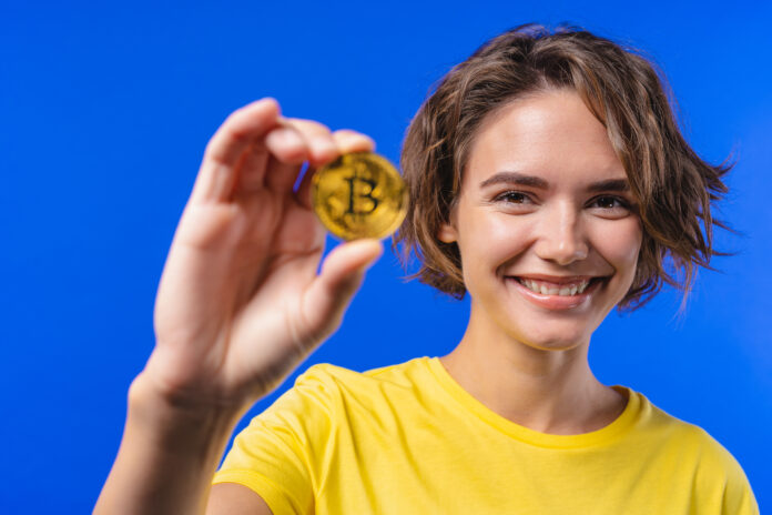 Woman with bitcoin, crypto currency. Golden coin on blue background. Digital exchange, popularity of BTC, symbol of future money, electronics industry, mining concept. Staking